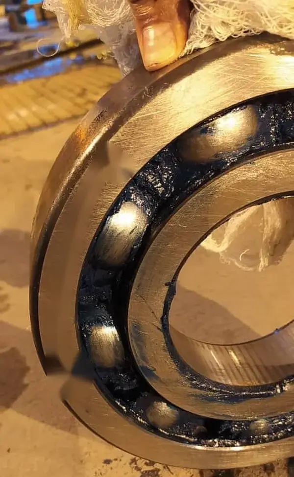 A deep groove ball bearing with a bright, shiny bore and black grease. A bore polished like this is what a ring turning on its shaft leaves behind.